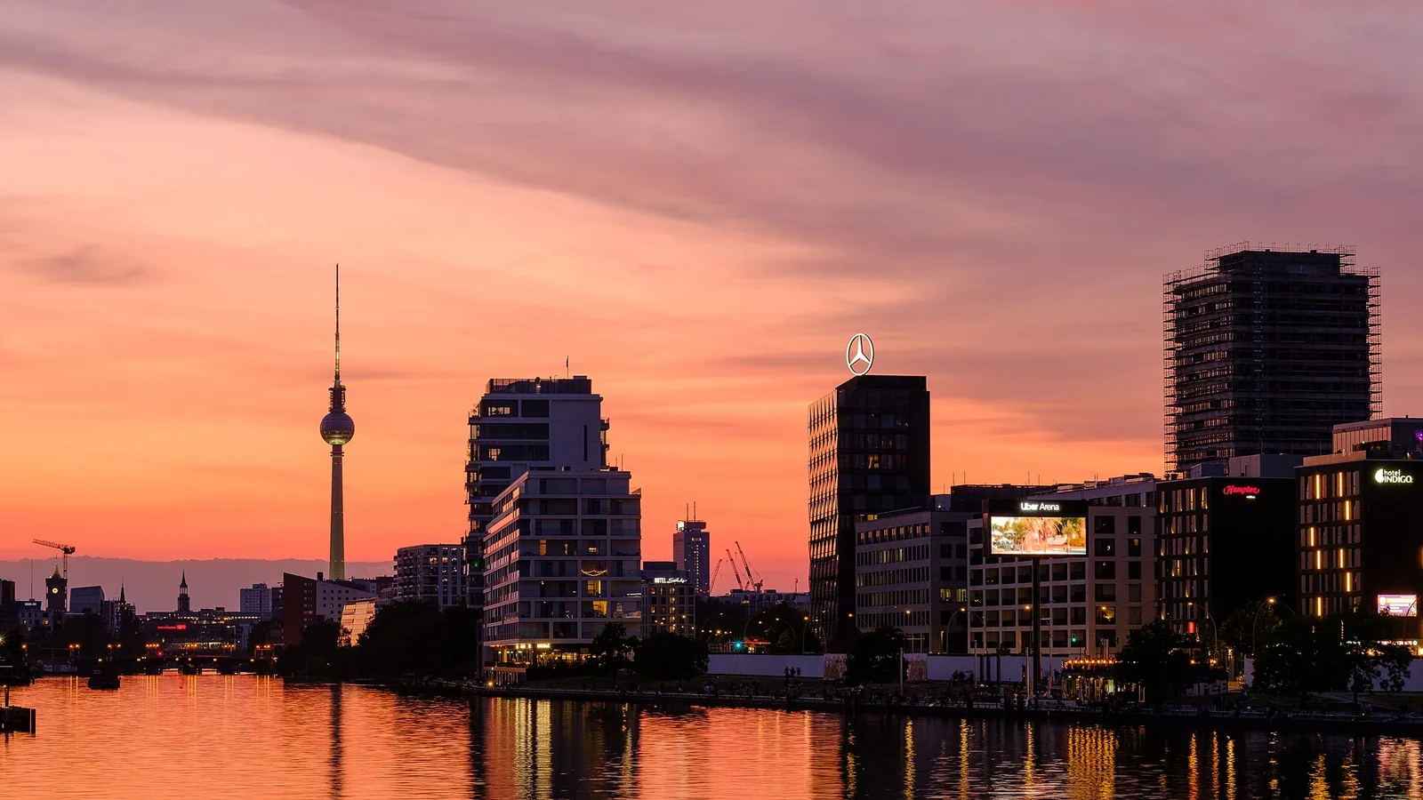 Berlin skyline and television tower reflected in the Spree beneath a pink sunset sky