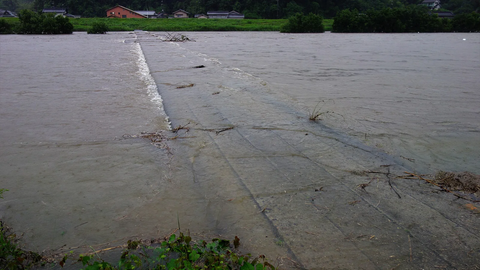 Floodwater covering a low bridge across the Ashida River in western Japan