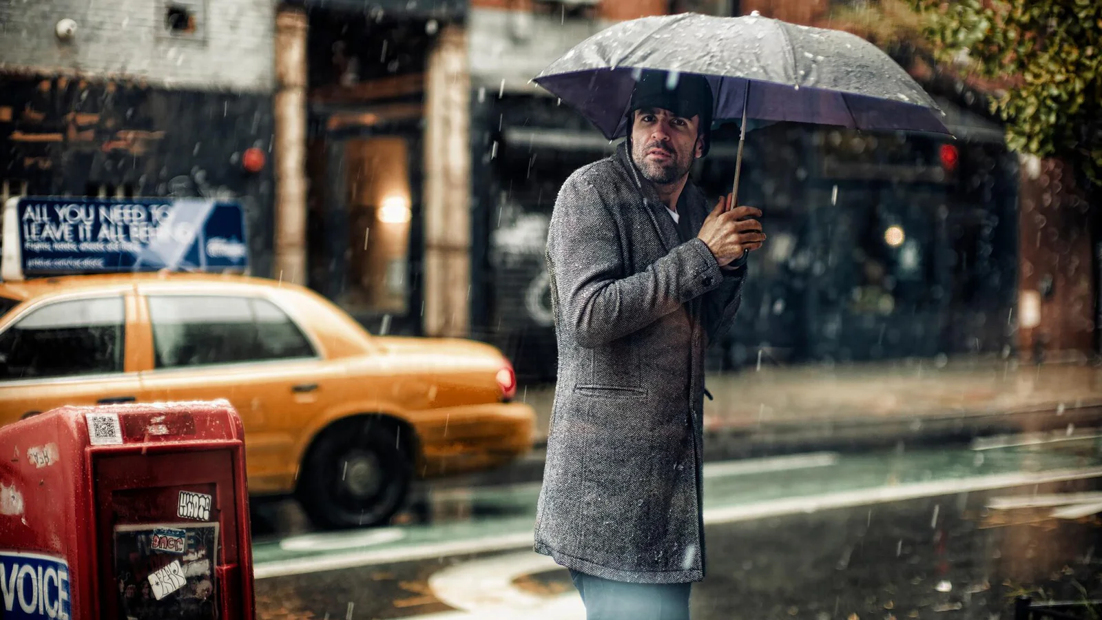 A pedestrian holding an umbrella during heavy rain on a New York City street