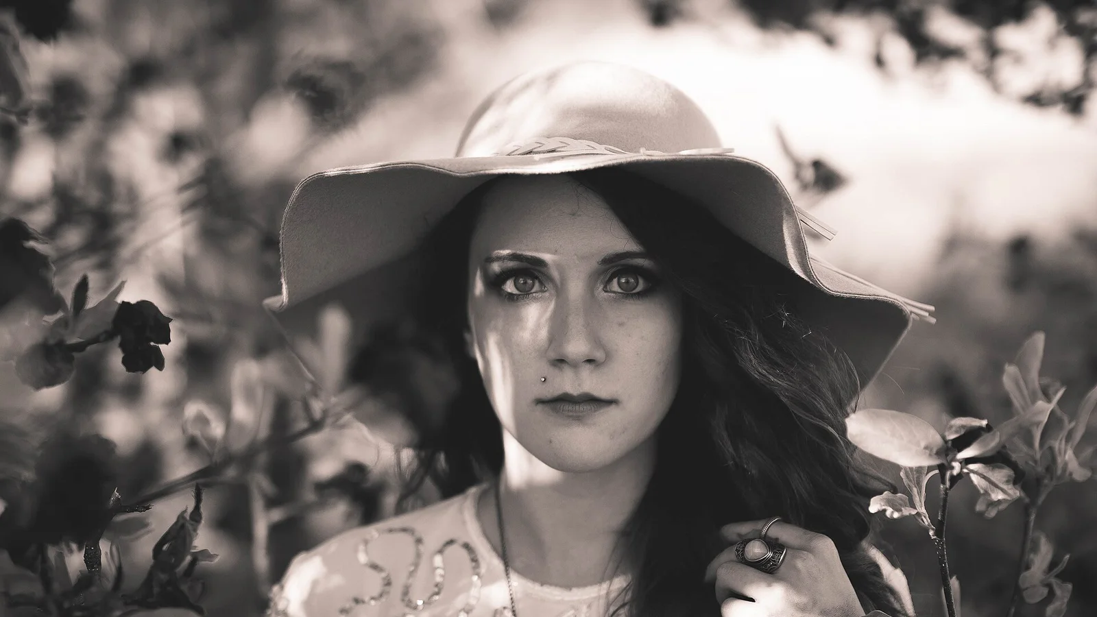 A person wearing a broad-brimmed sun hat among garden plants