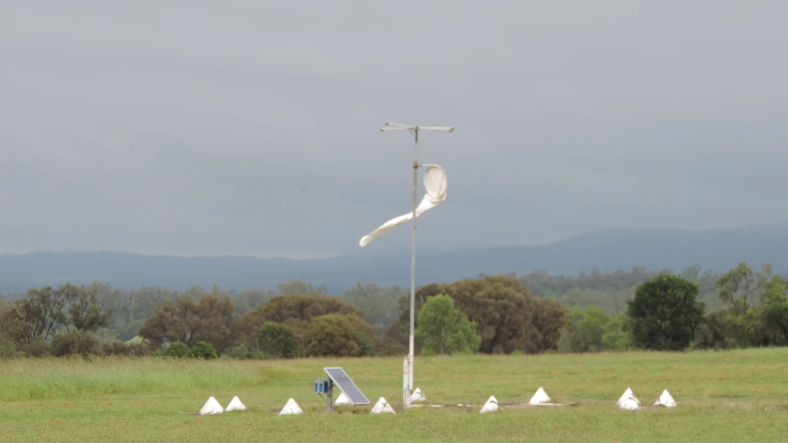 A windsock extended in the wind above a rural Australian airfield